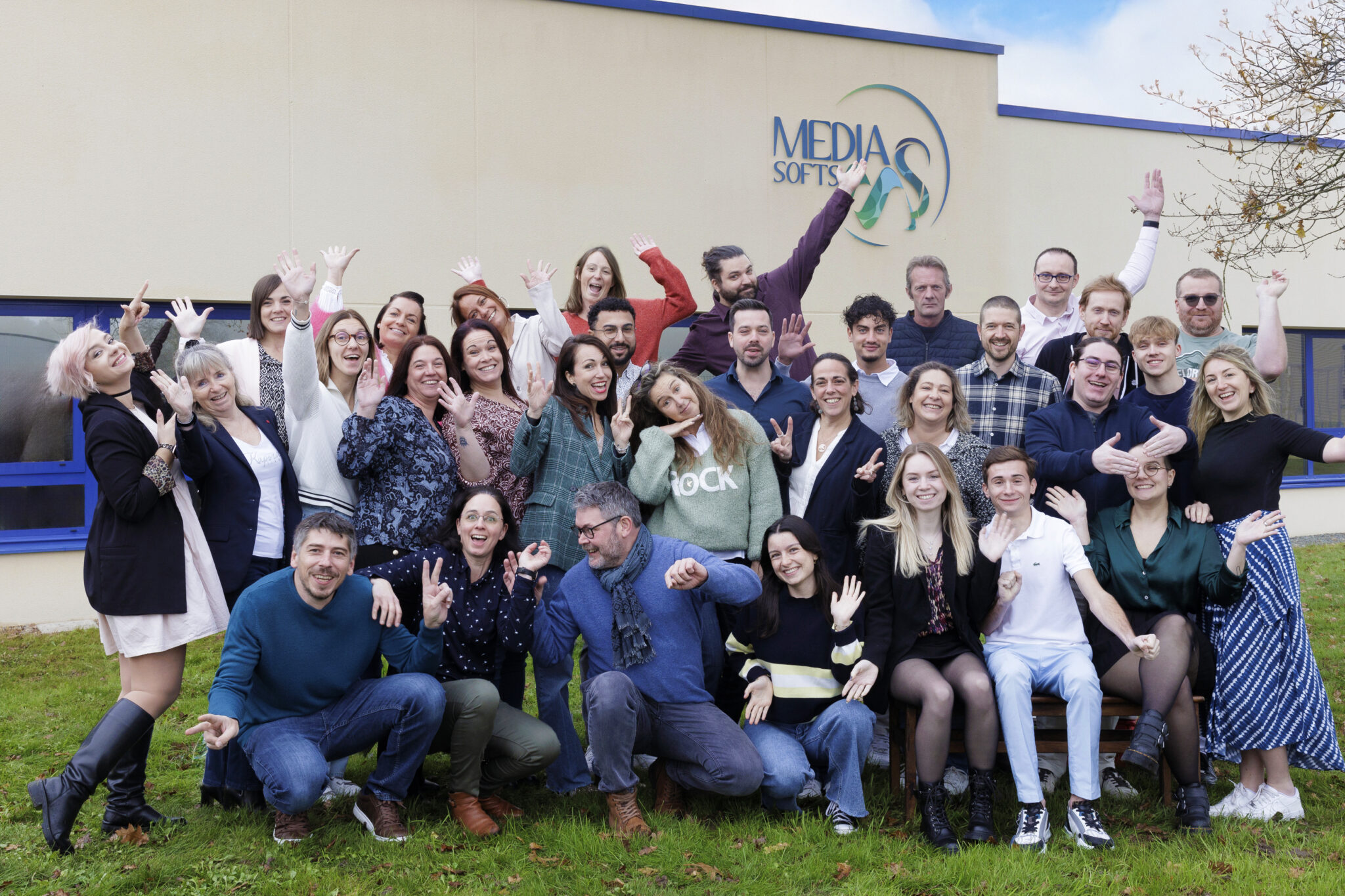 Équipe souriante devant bâtiment Media Softs.