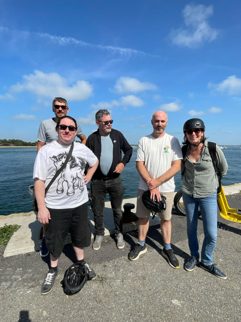 Cinq adultes au bord de l’eau avec trottinettes